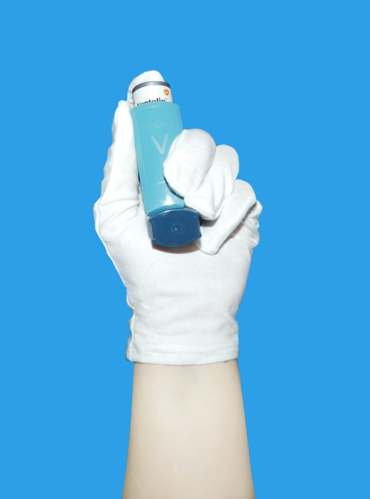A hand holding an inhaler 