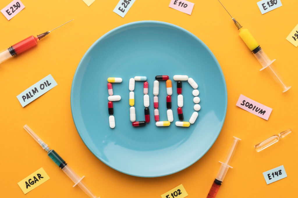 Food modifies with preservatives and additives. Showing pills and syringe around