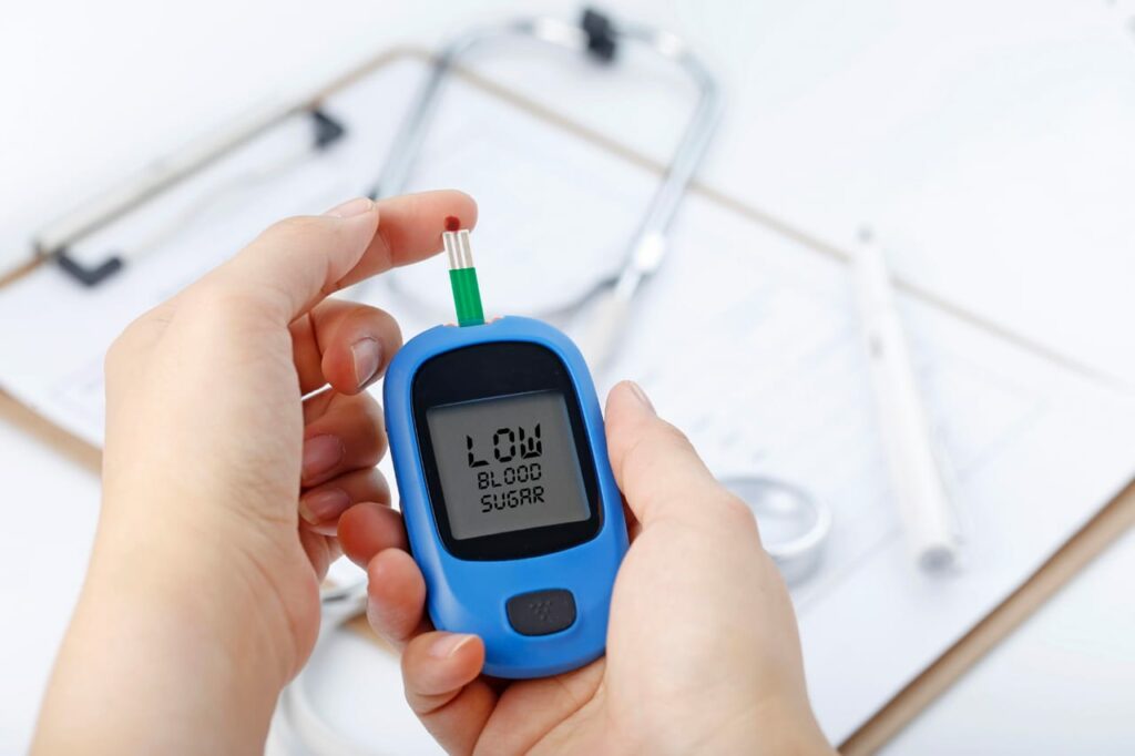 Image shows a person checking blood sugar on glucometer, and the result is low sugar, in a way to show effects of ancient grains on blood sugar levels