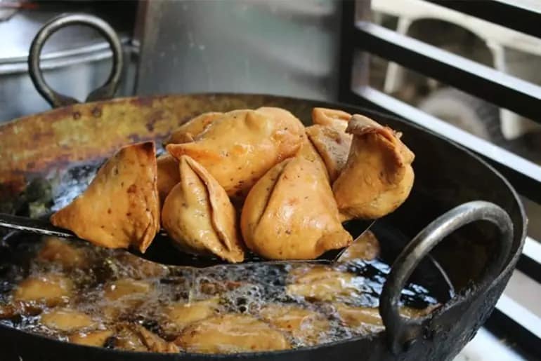A Medium to large size samosa gives us 250 ~ 310 calories and is loaded with carbs and fats. 

The cooking oil in which its cooked is the main culprit. Road side stalls use the same oil to fry multiple times making the oil stale. 

Most of the time, Hydrogenated oils (contains trans fats) are used to fry samosas. 

Trans fats are generated when liquid oils are turned into solid or semi-solid fats through hydrogenation, a process by which hydrogen is added to vegetable oil. 

This happens when oil is recycled during cooking, or when food is heated over and over again in the same oil it was cooked in. 

Hydrogenation increases the shelf life  and improves the taste making it tastier ~ crispiness of a samosa. Samosas  are very fattening. 

Cholesterol, digestion issues, trans fats, refined flour  are good reasons to think  before you snack on samosas. 

Snack on something more healthy . Burning 300 calories will require you to walk a average of approx. 6 km. 

Think what is important SAMOSA OR HEALTH. CHOICE IS YOURS.

Image from the web